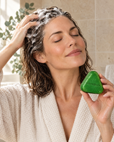 Woman massaging lather into her scalp while holding the UNUMZEKKA Scalp Revival Bar (product visualization)